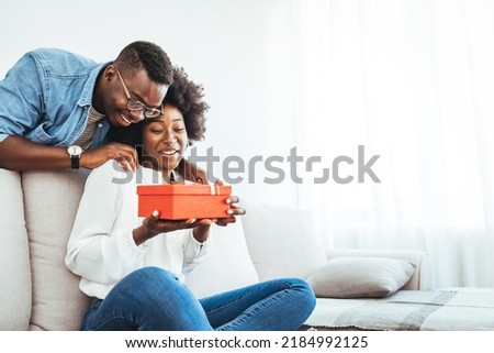 Valentine's day. Couple gives gift box to the Valentine's Day in the room. Beautiful young couple at home. Hugging, kissing and enjoying spending time together while celebrating Saint Valentine's Day