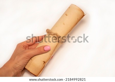 Scroll of ancient paper in a woman's hand on a white background, laid at an oblique angle