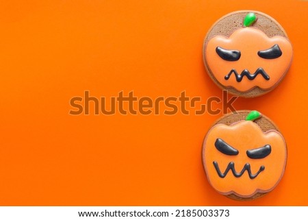 Halloween gingerbread cookies in a form of pumpkins on an orange backgound. Copy space. Top view.