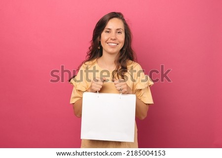 A photo of a woman holding a shopping bag while smiling at the camera 