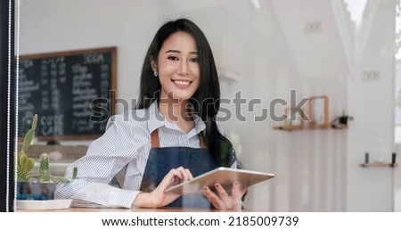 Startup successful small business owner sme beauty girl stand with tablet smartphone in coffee shop restaurant. Portrait of asian tan woman barista cafe owner SME entrepreneur seller business concept

