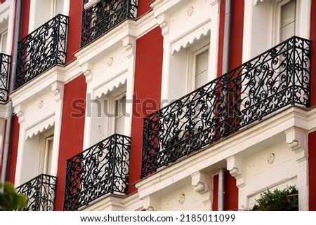    The facade of typical Spanish old house with beautiful balcony with various green plants in summer. Balcony with metal railings.                             Royalty-Free Stock Photo #2185011099