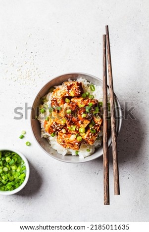 Korean tofu dubu-jorim - braised spicy bean curd with rice in a gray bowl, light background, top view, copy space. Asian vegetarian food concept. Royalty-Free Stock Photo #2185011635