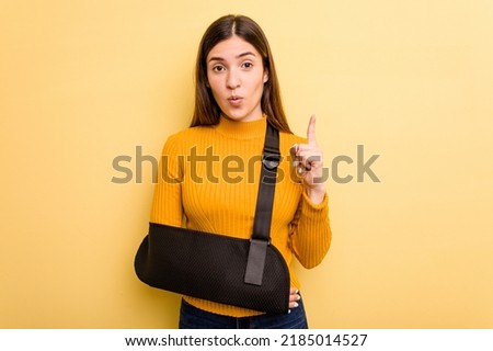 Young caucasian woman with broke arm isolated on yellow background having some great idea, concept of creativity.