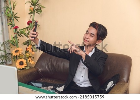 A young asian accountant taking a selfie after hours of computing worksheet balances. Taking a break after a whole day's work. Working at home.