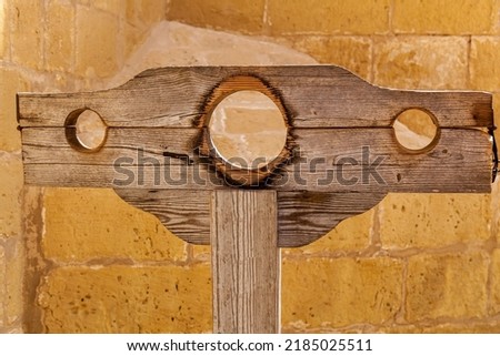 Medieval old wooden stocks for punishing criminals on the background of a stone wall