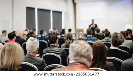 Speaker giving a talk in conference hall at business event. Rear view of unrecognizable people in audience at the conference hall. Business and entrepreneurship concept.