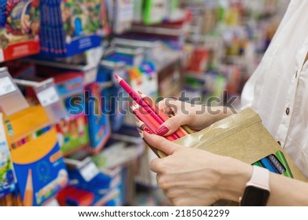 pencil on a stationery store. Young woman in the store buys colored pencils. Back to school. Side view of School supplies on shelf for students. Woman shopping in stationary. Selective focus Royalty-Free Stock Photo #2185042299
