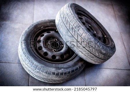 Two used car tires with wheels on the gray floor of the workshop Royalty-Free Stock Photo #2185045797