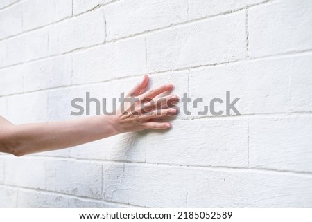 Woman's hand on the background of a white brick wall. A woman touches the old wall of the monastery. Royalty-Free Stock Photo #2185052589