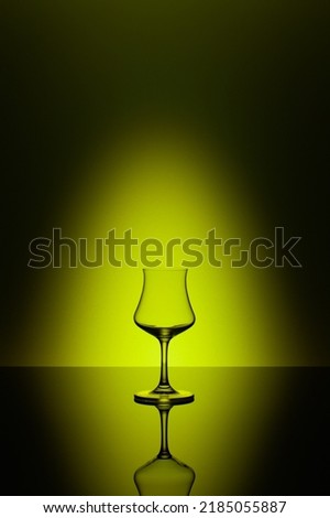 Rum tasting glass on the glass table and yellow background