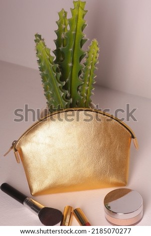 golden leather cosmetic bag with brush close up photo on white wall background