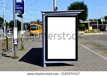 image composite of bus shelter at bus stop of blank light box and glass structure. green street setting. urban background. glass design. white poster ad commercial poster space. blurred background.