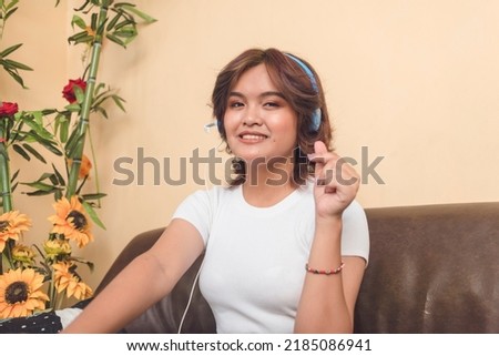 Business Process Outsourcing Agent shows a heart sign like the Korean. Working remotely at a sofa in her condominium unit.
