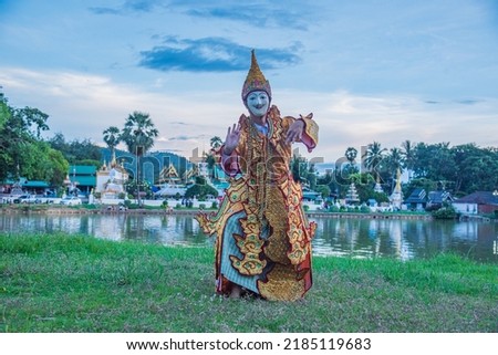 Wearing a mask, wearing a golden dress, and posing for music, dancing, performing Burmese arts