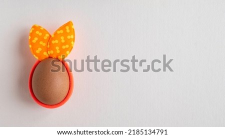 Egg with spots rabbit ears on white paper background. Copy space. Flat lay.