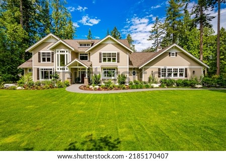 Exterior photo of luxurious house on landscaped lot with blue sky green foliage craftsman style windows vaulted entry 