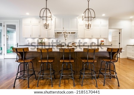 rustic modern farmhouse kitchen with white cabinets wrought iron and wood chairs eating counter and light fixtures Royalty-Free Stock Photo #2185170441