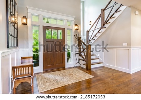 front entry foyer of a luxurious home rich wood tones staircase bench with a welcoming feel Royalty-Free Stock Photo #2185172053
