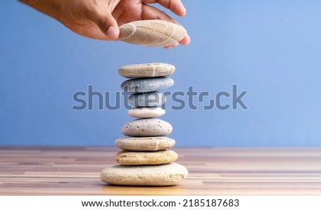 Hand stacking pebbles to make shape of hourglass as a symbol of time management. Concept of meditation, slow down and controlling time. Royalty-Free Stock Photo #2185187683