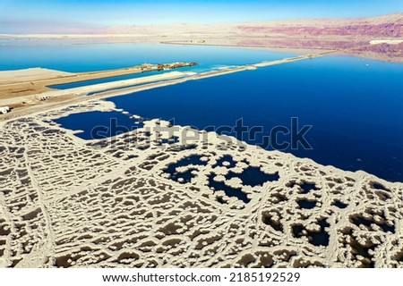 Dead Sea. The blue water is surrounded by pink mountains. Evaporated salt forms bizarre patterns on the water. Sunny winter day. The picture was taken by a drone from a aerial view. Israel.