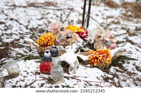 Old rural cemetery in winter. Neglected graves with snow in the old cemetery in winter. Burned candles after All Saints Day on November 11.