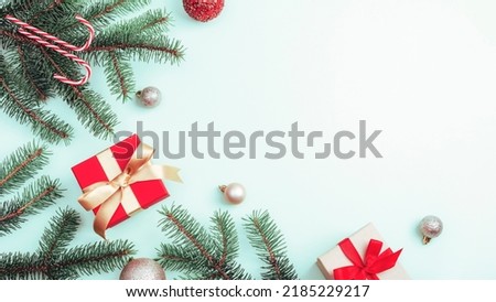 Christmas decorations, gift boxes, fir branches and candy cane on light background. Top view, flat lay, copy space.