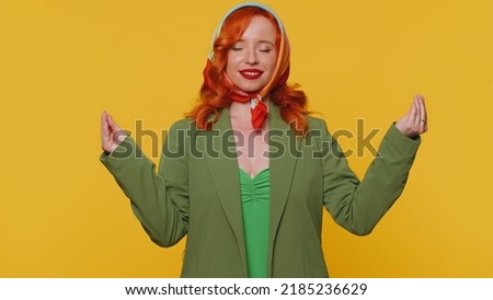 Keep calm down, relax, inner balance. Woman breathes deeply with mudra gesture, eyes closed meditating with concentrated thoughts peaceful mind. Redhead adult girl isolated on yellow studio background