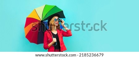 Portrait of happy smiling young woman photographer with film camera and colorful umbrella on blue background, blank copy space for advertising text