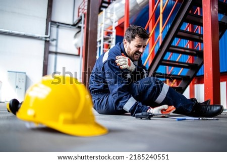 Injury at work. Factory worker fell down and injured shoulder at work. Royalty-Free Stock Photo #2185240551