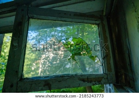 Low angle of grungy window with shabby lumber frame and broken glass on summer day inside desolate building Royalty-Free Stock Photo #2185243773