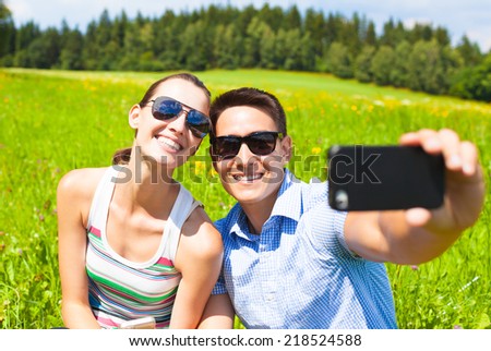 Beautiful young couple taking picture with smart phone