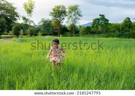 Happy girl running at grass field outdoor.