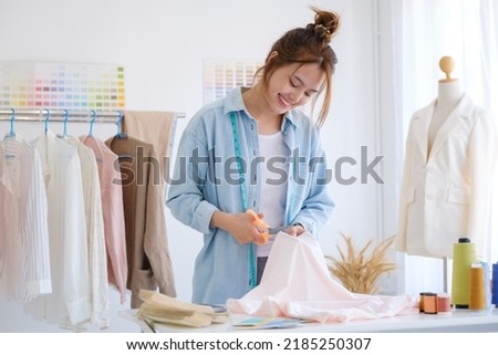Fashion designer working in studio, cutting drawing, sewing dress