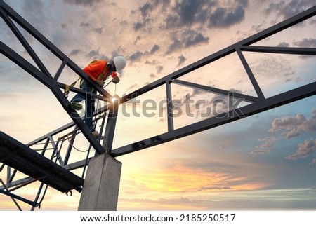 Steel roof truss welders with safety devices to prevent falls from a height in the construction site. Royalty-Free Stock Photo #2185250517