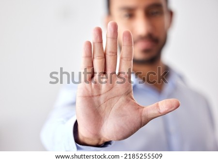 Closeup of the hand of a business man showing stop, saying no or not accepting a deal in an office at work. Male corporate worker making hand gesture not agreeing to a statement or refusing an Royalty-Free Stock Photo #2185255509