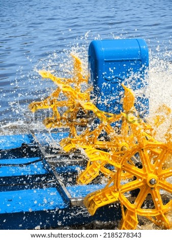 Paddle wheel aerator spinning to supply oxygen in aquaculture pond Royalty-Free Stock Photo #2185278343