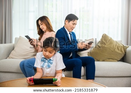 Family don't care about each other. Asian parents ignore their child and looking at their mobile phone at home, gadgets dependence overuse internet social media addiction on sofa living room Royalty-Free Stock Photo #2185331879