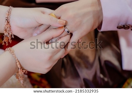 Hand of The groom wears a wedding ring to the bride.