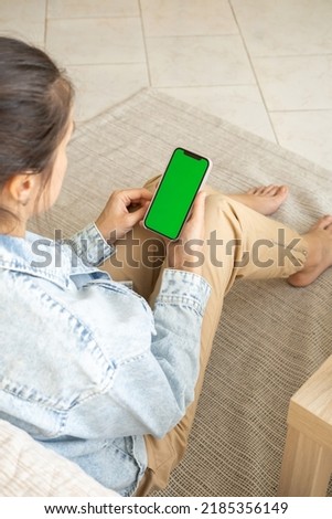 Young Woman at Home Uses Green Mock-up Screen Smartphone. Close-up of woman hands holding chroma key green screen
