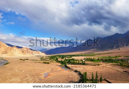 Desert valley, few huts and trees, barren mountains and dramatic blue sky. Beautiful scenic view from Stagna Gompa (Stakna monastery), Leh district, Ladakh, Himalayas, Jammu Kashmir, Northern India