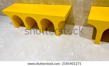 a yellow seat that is usually used as a place to wear shoes