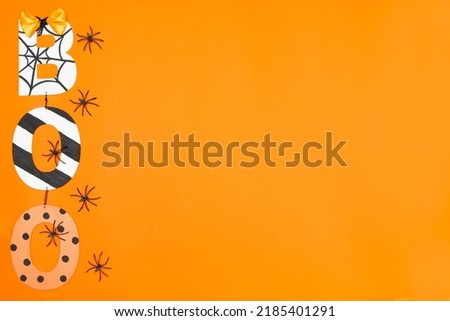 BOO lettering in Halloween style. Orange background and black spiders. Place for text. Copy space. Halloween concept. Flay lay. Top view.