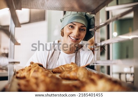 Female baker at the kitchen holding croissant Royalty-Free Stock Photo #2185401455