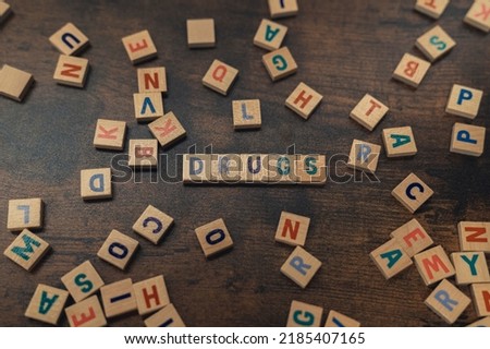 The dangerous concept of drug abuse depicted by symbolic word puzzles creating the word DRUGS from square wooden letters in the shades of blue. High quality photo