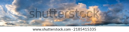 Panorama sunset sky and dark clouds.Fluffy cloud in the black sky background.Vivid sky on dark cloud before summer storm with color rainbow. Royalty-Free Stock Photo #2185415335