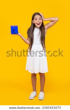 surprised teen child hold gift box on yellow background