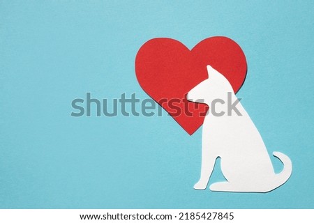 Paper silhouette of a dog and a red heart on a blue background. Flat lay, place for text. Veterinary care or animal care.