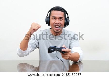 Asian man clenched fist showing winning gesture when playing game