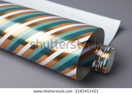 Roll of striped wrapping paper on grey background, closeup